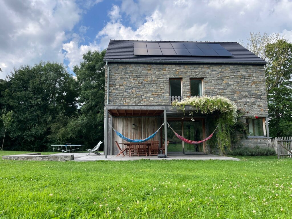 L’Ecologis, maison en pierre avec panneaux solaires, terrasse et hamac, au milieu du jardin
